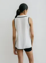 Blusa negra sin mangas con cuello camisero y abertura a los costados, con ribete color beige.