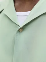 Camisa de manga corta color verde menta, con cuello cubano y cierre frontal con botones.