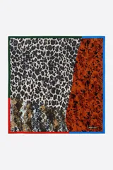 Pañuelo cuadrado con diseño de patchwork que integra diversos estampados animales, incluyendo leopardo y serpiente, en una paleta de colores tierra y neutros. Cuenta con bordes decorativos en colores verde, azul y rojo, y el logotipo de Bimba y Lola en una esquina. Fabricado en poliéster reciclado.