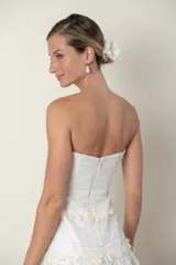 Vestido strapless color marfil con detalles de encaje y flecos.