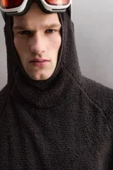 Sudadera de corte regular fit confeccionada en tejido polar con textura efecto pelo. Presenta cuello subido con capucha integrada, manga larga ranglán y acabados con cinta elástica. El bajo es asimétrico, siendo más largo en la parte posterior.
