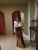 Falda larga de cuero en diseño de paneles bicolor, combinando tonos marrón y bordó. Presenta cintura ajustable con lazo y un diseño de borde lateral irregular con tajos.