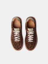 Zapatillas de cuero con estampado animal print tipo leopardo, cordones blancos y suela plana de goma.