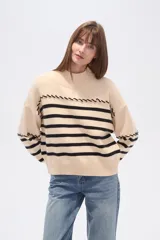 Sweater beige con rayas horizontales negras, cuello alto y corte holgado.