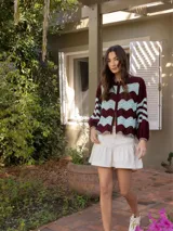 Campera de tejido de punto con diseño de ondas en colores azul y crudo. Posee cierre frontal doble (superior e inferior) y mangas largas con puños ajustados.