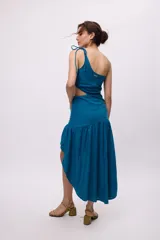 Vestido azul con bretel fino, escote asimétrico de un hombro, corte a la cintura con recorte en el lateral y falda midi con volados irregulares.
