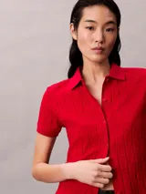 Chomba roja de Calvin Klein confeccionada en algodón con textura jacquard y estampado integral del logo. Cuenta con cuello polo, manga corta, cierre frontal con botones y detalles acanalados en los puños y el dobladillo.