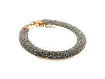 Gargantilla tubular de metal dorado completamente revestida de microcristales brillantes en tonos plateados e iridiscentes. Cuenta con cierre de mosquetón y cadena de alargue.