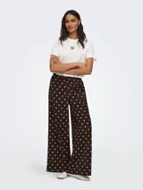Pantalón suelto color marrón con estampado de lunares blancos, tiro medio y cintura elástica con cordón de ajuste.