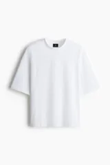 Remera de algodón en color blanco, con cuello redondo, mangas cortas amplias y corte oversized de estilo relajado.