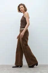 Pantalon de tiro medio y corte wide leg, confeccionado en pana color tostado. Presenta costuras verticales decorativas en el frente y bolsillos laterales.