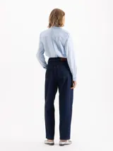 Pantalón de jean azul oscuro de tiro alto y silueta slouchy, con costuras a la vista y cierre frontal con botón metálico.