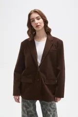 Blazer de pana color marrón, con corte holgado, cuello solapa y cierre frontal con dos botones. Presenta bolsillos laterales con solapa y un bolsillo superior en el pecho.
