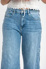 Jean de corte wide leg con tiro medio, confeccionado en denim de algodón. Presenta un diseño de pierna ancha con costuras verticales frontales que estilizan la silueta, cierre de botón y cremallera, y bolsillos clásicos.