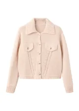 Chaqueta de punto color beige, de corte corto, con cuello camisero, bolsillos frontales con solapa y botones metálicos.