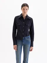 Camisa entallada de poplín color negro, con cuello clásico, cierre frontal de botones, mangas largas con puños anchos y bolsillos frontales con tapa.