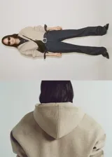 Chaqueta tipo bomber con capucha, confeccionada en tejido de poliéster con textura suave. Presenta cierre frontal de cremallera, mangas largas con puños elásticos y cintura acanalada.