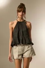 Top negro de cuello halter con frunces, diseño holgado y corte cropped con volado en el ruedo.