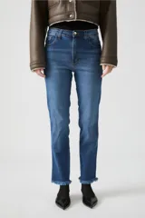 Jean azul de tiro alto, calce ajustado y ruedo desflecado.