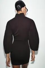 Vestido corto de tejido de punto elástico con cuello alto, manga larga y cierre posterior con cremallera.