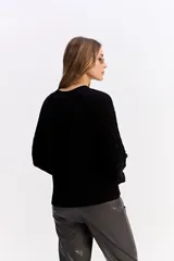 Buzo de punto negro con diseño de trenzas en relieve, cuello redondo y mangas largas.