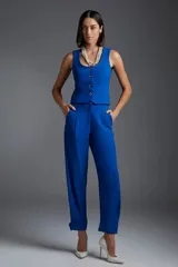 Pantalón de vestir azul eléctrico, de corte recto, con bolsillos laterales y traseros. Se ajusta a la cintura con cinturón de cuero marrón.