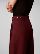 Pantalón chino de pierna ancha y talle alto Calvin Klein, color bordó, con cierre de doble botón y cremallera, bolsillos laterales y detalles de costura frontal.