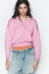 Sweater tipo polo de punto liso, con cuello solapa, manga larga y bolsillo delantero de plastrón. Presenta cierre frontal con botones y puños y ruedo acanalados.
