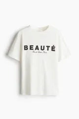 Remera de algodón con cuello redondo y corte holgado. Presenta un estampado frontal con la palabra 'BEAUTÉ' en letras grandes y una leyenda debajo.