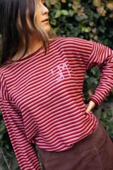 Remerón de manga larga con diseño de rayas horizontales finas en tonos tierra. Presenta un corte holgado y cuenta con un bordado artesanal en color rojo en el pecho.