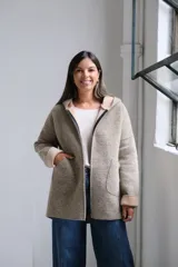 Tapado de paño con capucha, color beige, con cierre frontal, bolsillos laterales y puños vueltos en tono más claro.