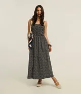Vestido midi evasé de tricolina color negro con estampa de pequeños corazones blancos, escote recto, tirantes finos, cuerpo con lastex y recorte fruncido en la cintura.