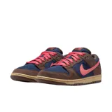 Championes Nike SB Dunk Low con diseño de paneles en gamuza azul marino y marrón, acentuados con un swoosh y cordones en color rosa vibrante, sobre una suela de goma en tono caramelo.