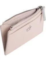 Tarjetero compacto de poliuretano color rosa pálido con textura saffiano. Cuenta con un bolsillo superior con cierre metálico plateado y el logo metálico de Calvin Klein en el frente.