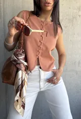 Chaleco color terracota con botones frontales y corte irregular en el ruedo. Sin mangas y con cuello redondo.