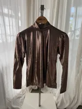 Polera de manga larga color cobre con efecto brillante y frunces en los hombros, cuello alto y caída recta.