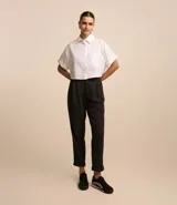 Pantalón jogger negro con finas rayas verticales blancas, cintura de sastrería con cierre de botón y cremallera, pliegues delanteros y bajo plegado.