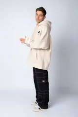 Buzo tipo canguro color negro con capucha y cordones ajustables. Presenta un pequeño estampado en el pecho con la silueta de Mickey Mouse y un detalle a cuadros en color verde.