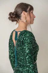 Vestido corto verde esmeralda de paillettes con escote en V y mangas largas. Presenta detalle de strass en el escote y la cintura, y corte recto.