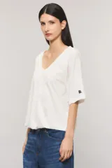 Remera oversize color blanco, confeccionada en jersey Pima flamé de algodón. Cuenta con escote en V, mangas cortas con detalle de bordado en la manga y cintura con elástico que genera un efecto balloon.