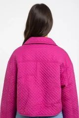 Campera corta de diseño acolchado con textura capitoné, color fucsia. Presenta cuello camisero, cierre frontal con botones a tono, bolsillos con solapa en el pecho y mangas largas con puños elásticos.