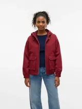 Campera corta tipo parka de color bordó, con capucha ajustable con cordón, cierre frontal metálico y bolsillos frontales con solapa. Presenta mangas largas con puños elásticos.