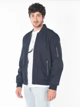 Campera bomber azul marino de poliéster con cierre frontal, puños y dobladillo de punto canalé, bolsillos exteriores con cierre y logo CK bordado en el pecho.