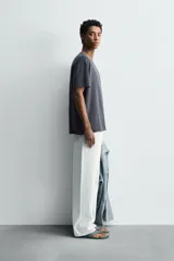 Camiseta relaxed fit de algodón ligero, color gris oscuro, con cuello redondo y manga corta con acabados irregulares. Pertenece a la colección especial Origins.