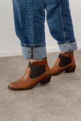 Botín negro de cuero con elásticos laterales, taco bajo y tirador trasero.