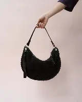 Bolso tipo hobo de gamuza color marrón oscuro, con diseño de media luna y detalles trenzados en los bordes. Cuenta con cierre superior, tiradores de cuero anudados y correa ajustable y desmontable con herrajes metálicos.