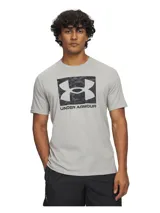 Remera de manga corta Under Armour, color gris claro, con cuello redondo acanalado y estampado frontal del logo de la marca sobre un fondo con diseño de camuflaje.
