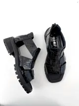 Sandalias negras de cuero con textura escamada, corte asimétrico y suela track.