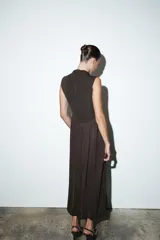 Vestido largo sin mangas con cuello subido, confeccionado con una parte superior lisa y falda de tul con caída fluida. Cuenta con cierre de cremallera oculta en la espalda.