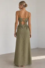 Vestido largo verde militar de tirantes finos, con aberturas en la cintura y detalles de flecos en el corpiño y la cadera.